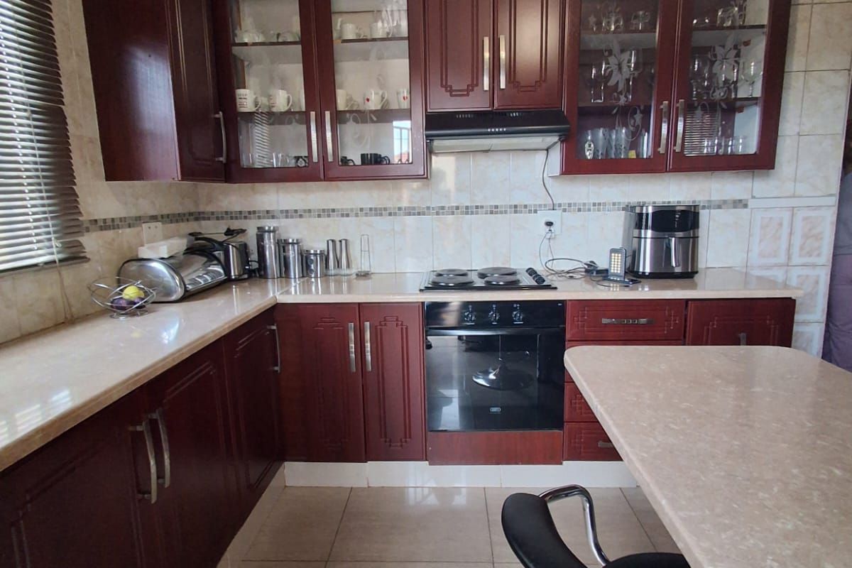 A functional kitchen featuring dark wood cabinetry, stone-look countertops, a built-in oven, and a hob with an extractor fan.