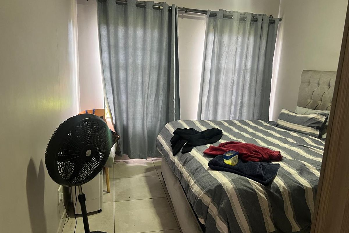 A bedroom featuring tiled flooring and dual windows dressed with curtains, providing a functional and comfortable sleeping space.