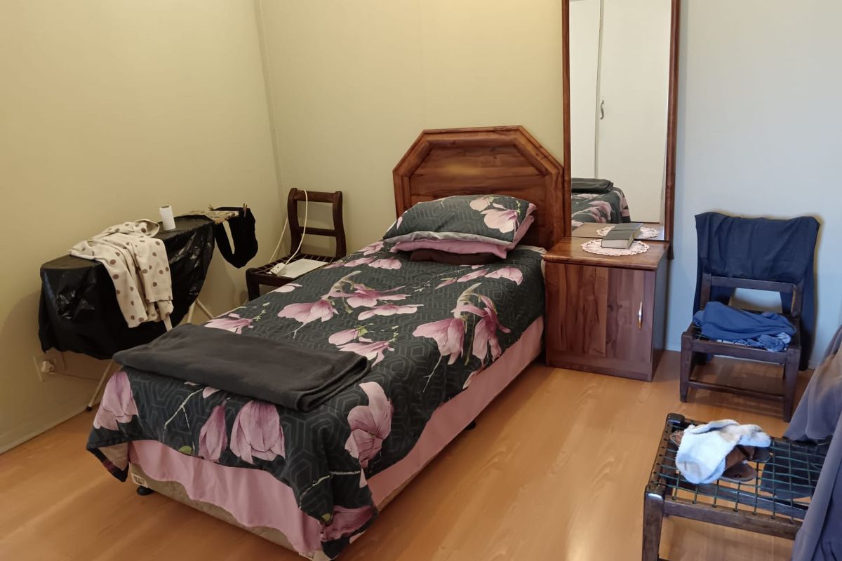 A functional bedroom featuring laminate flooring and a built-in wardrobe with a mirrored door.