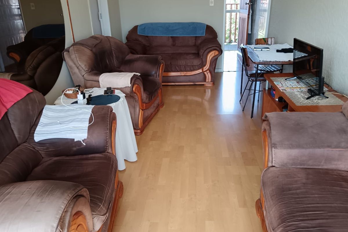 A living room area featuring light wood-look laminate flooring and access to an outdoor balcony.