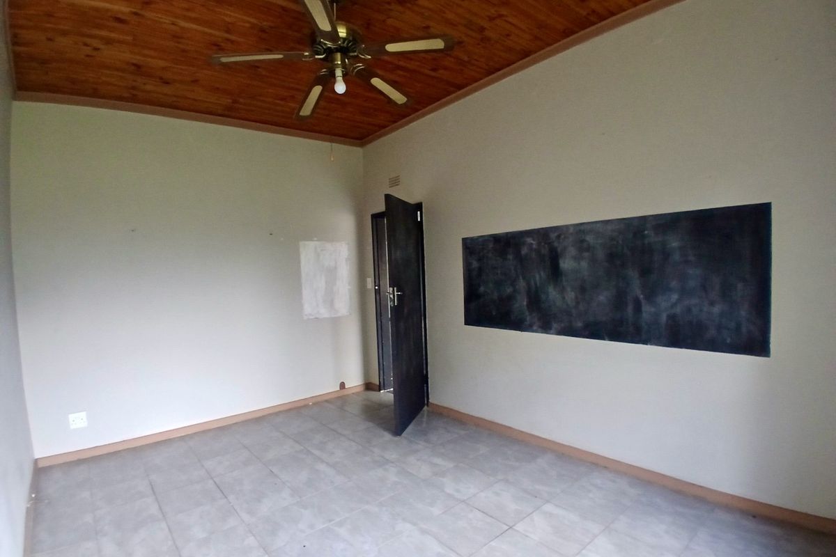 An empty bedroom featuring a wooden ceiling, ceiling fan, tiled flooring, and a dark painted feature wall.