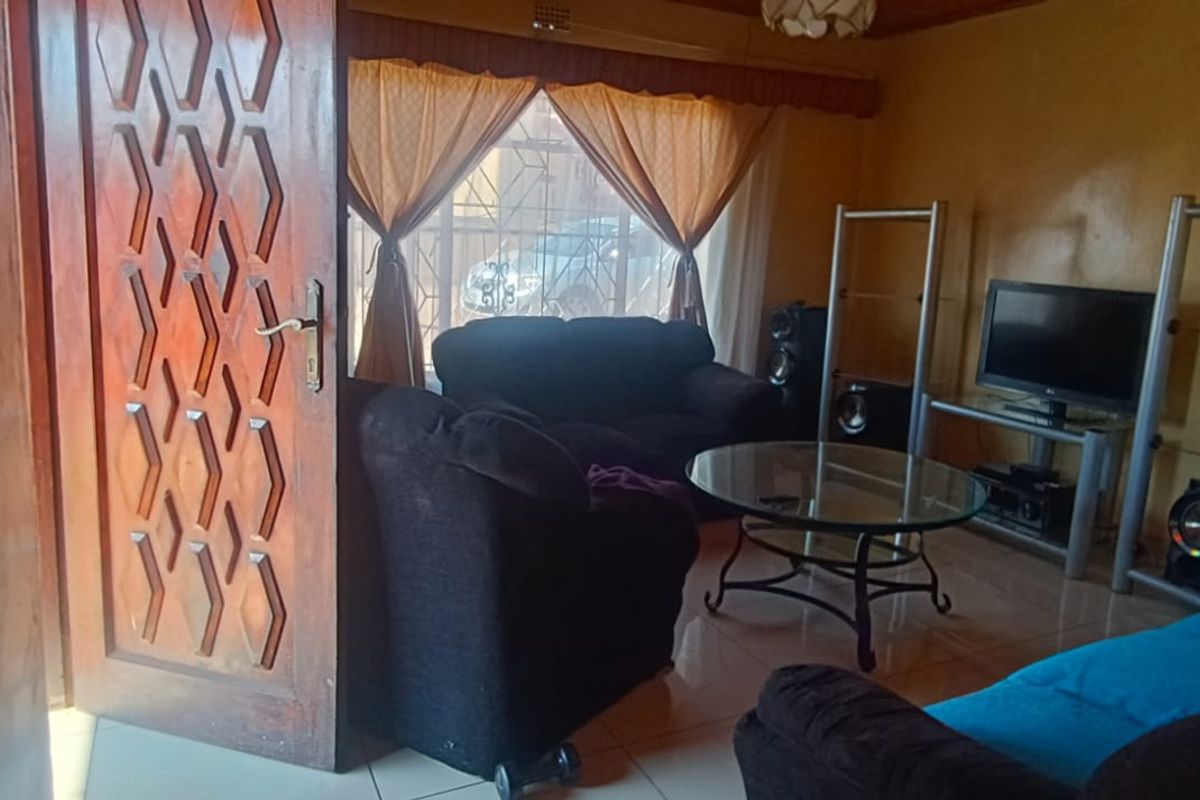 A living room featuring tiled flooring and a solid timber entrance door, providing a functional space with direct access to the exterior.