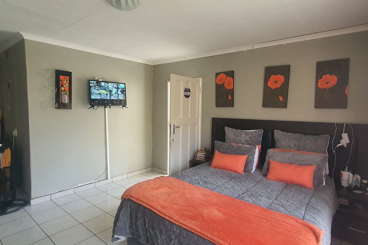 A functional bedroom featuring tiled flooring, neutral wall tones, and a standard door, providing a comfortable and practical living space.