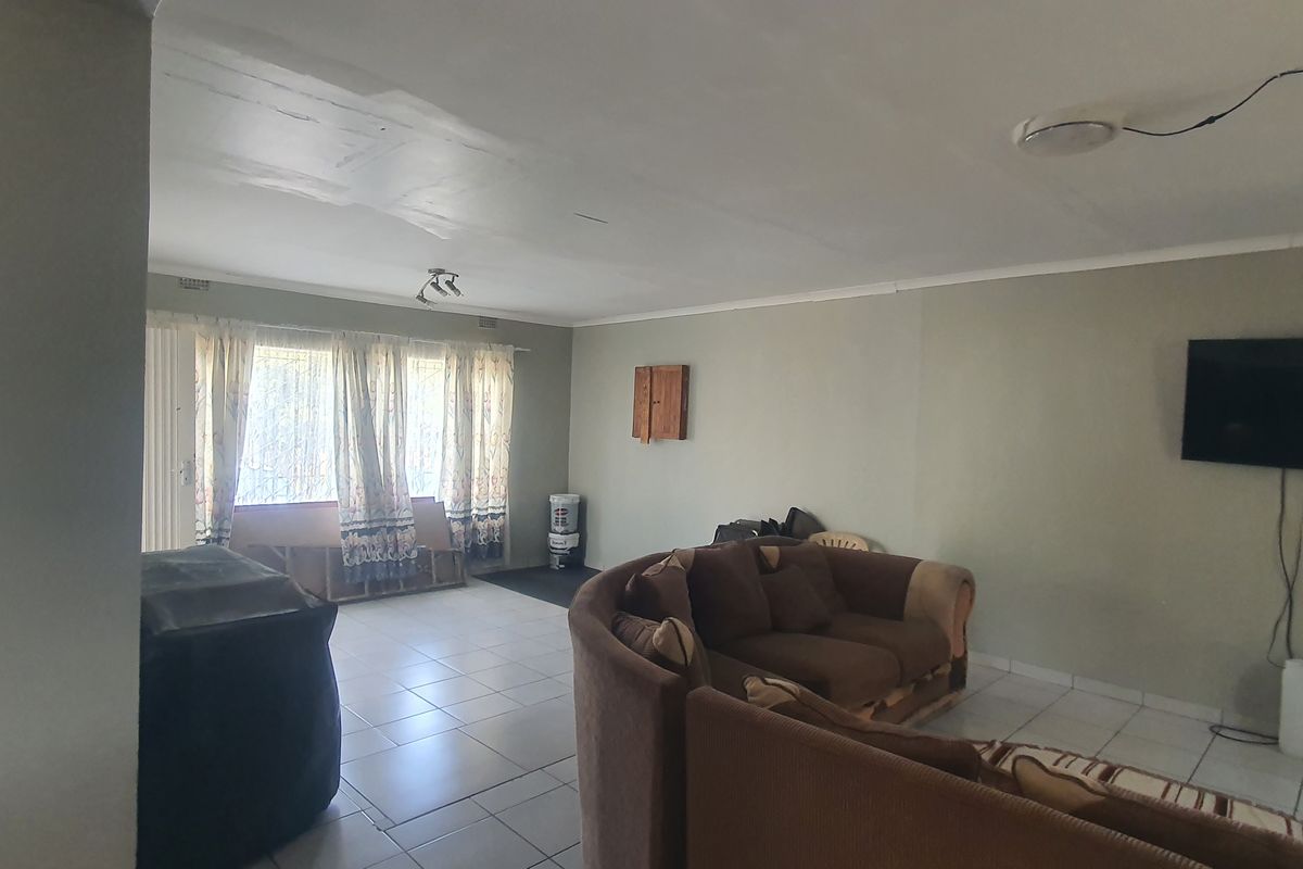 A spacious living area featuring tiled flooring, neutral wall tones, and large windows that allow for natural light.