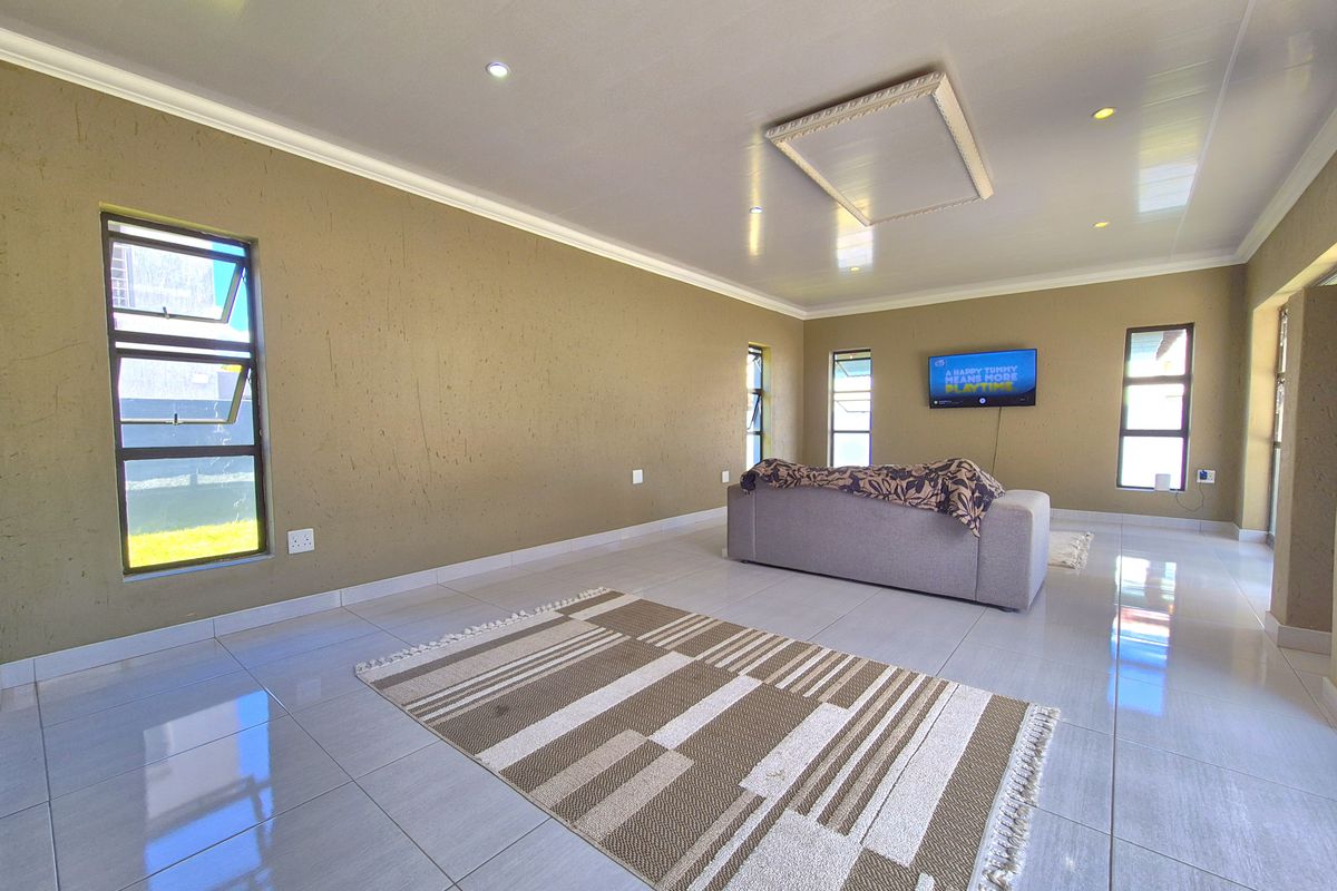 Spacious living area featuring large format floor tiles, recessed downlighting, and multiple windows providing natural light.