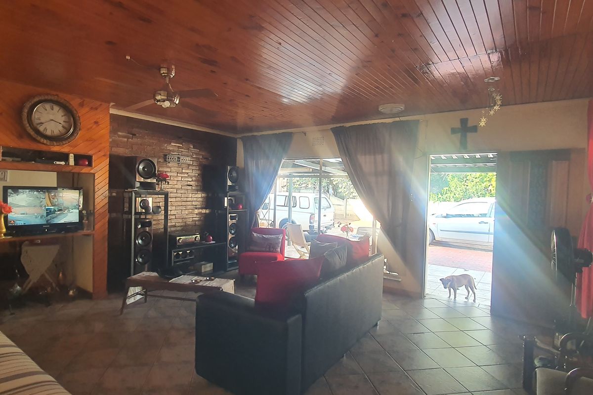 Spacious living room featuring a distinctive timber-clad ceiling, exposed brick feature wall, and direct access to the outdoor patio area.