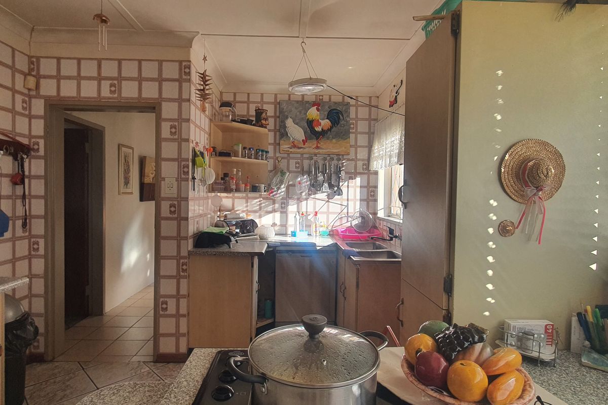 A dated kitchen featuring original tiled walls, laminate countertops, and built-in cabinetry, offering significant potential for a modern renovation.