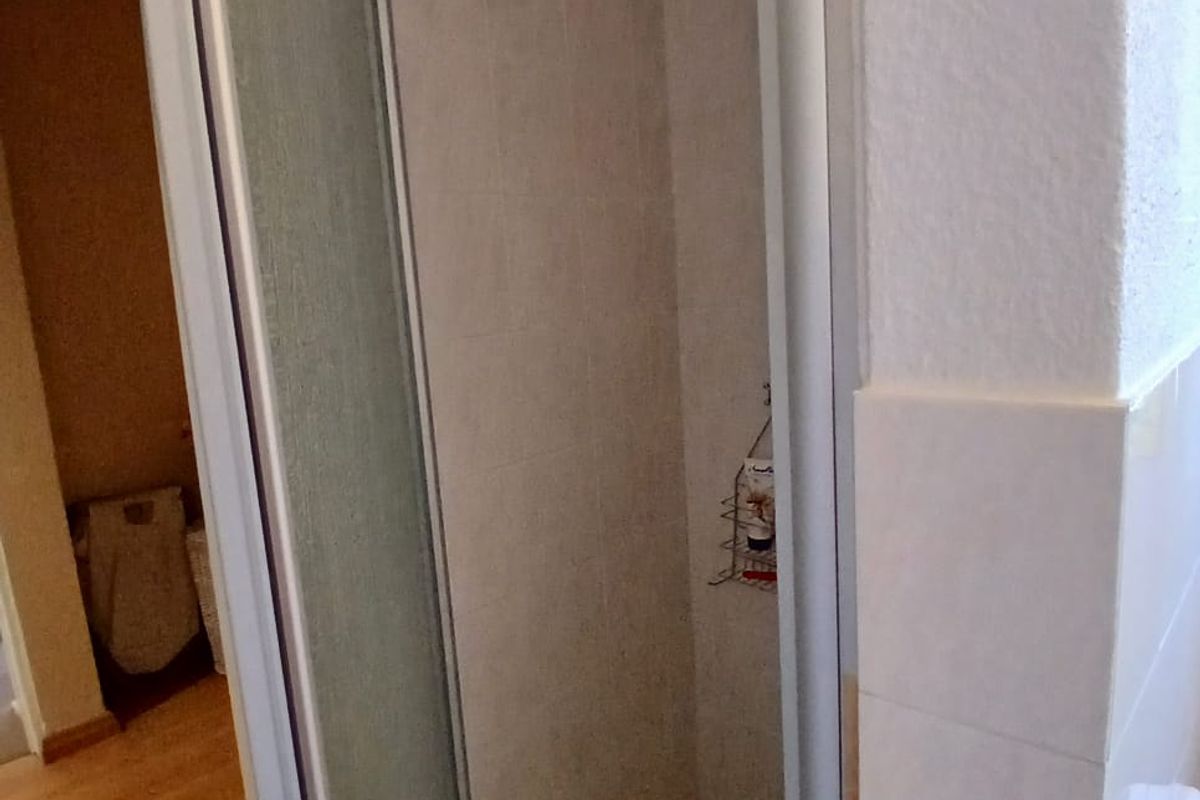 A compact shower stall featuring a framed glass door, tiled walls, and a tiled floor base within a bathroom setting.