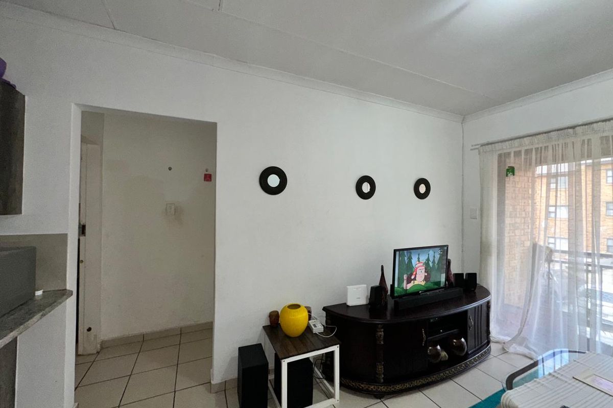 A living room featuring tiled flooring, coved ceilings, and a sliding glass door providing access to the exterior.