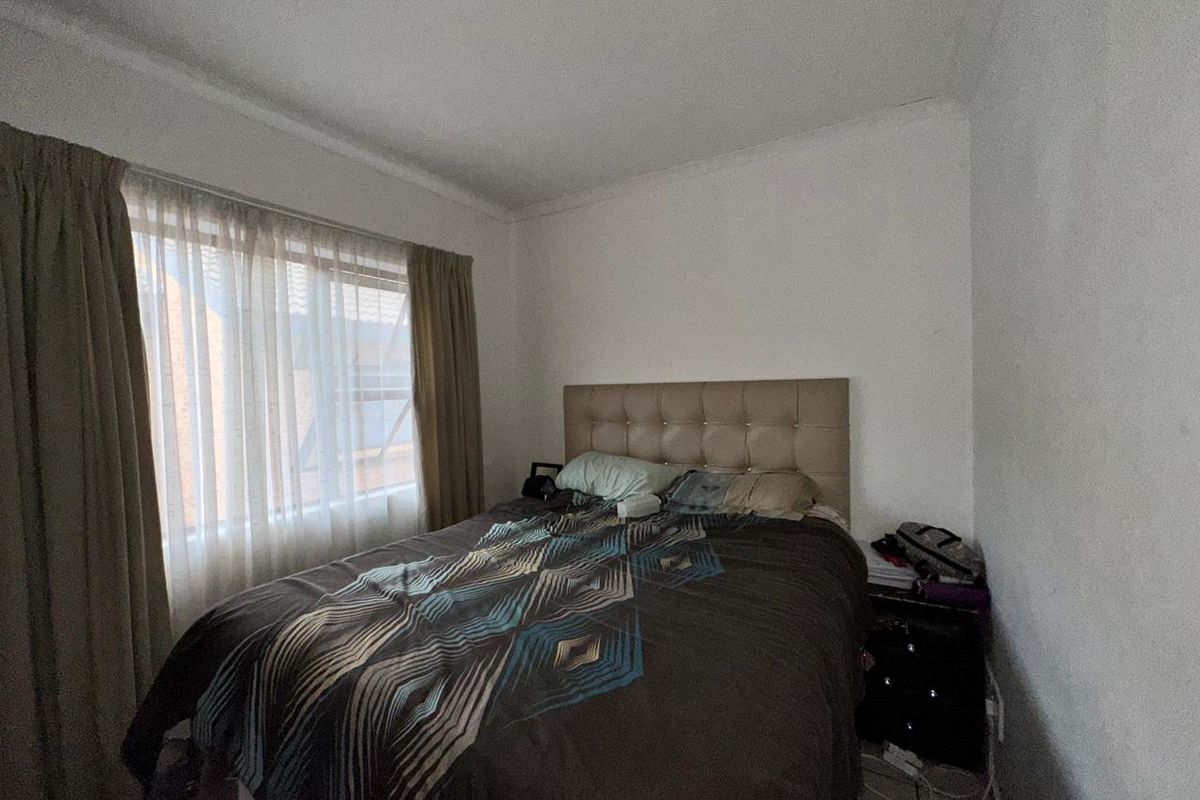 A standard bedroom featuring tiled flooring and a window with curtains, providing a functional space for rest.