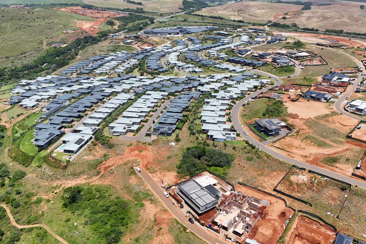 Aerial view of a residential estate development featuring established homes and ongoing construction of new residential properties on vacant land plots.