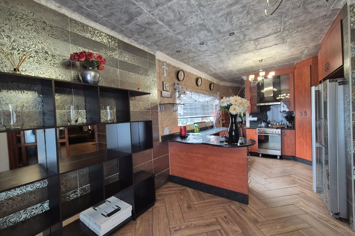 A kitchen featuring wood-finish cabinetry, dark granite countertops, a stainless steel stove with extractor fan, and patterned tile flooring.