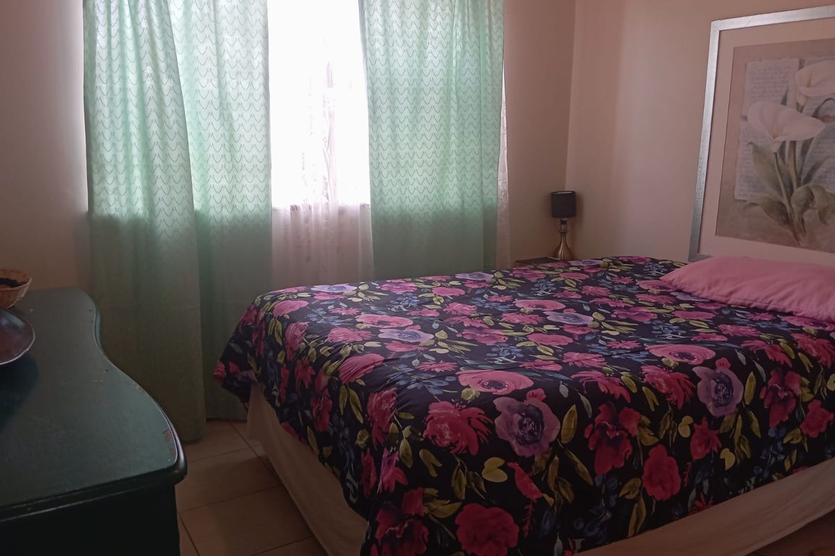 A standard bedroom featuring tiled flooring and a window with curtains, providing a functional and comfortable living space.