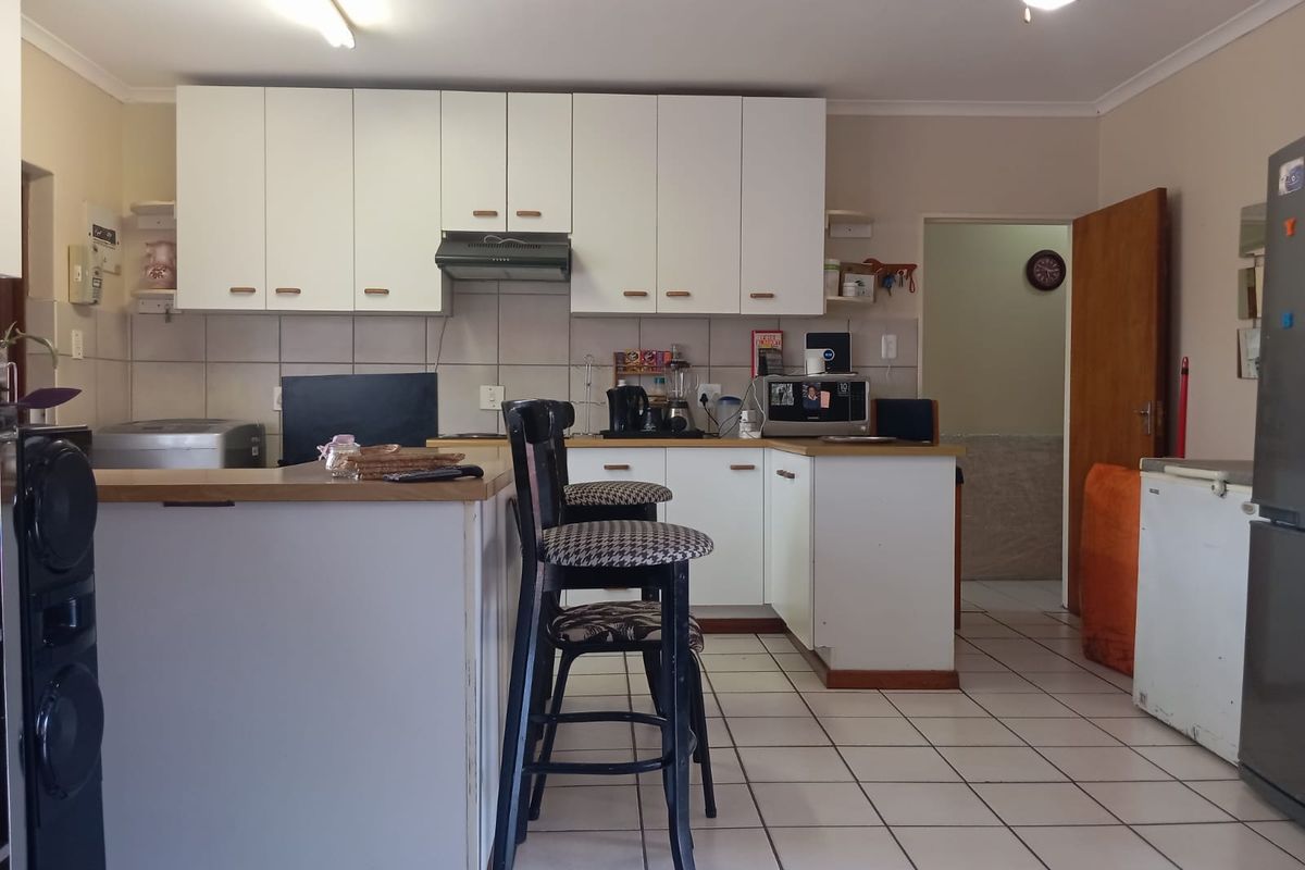 A functional kitchen featuring white cabinetry, tiled flooring, and a breakfast bar, offering a practical layout with potential for modern updates.