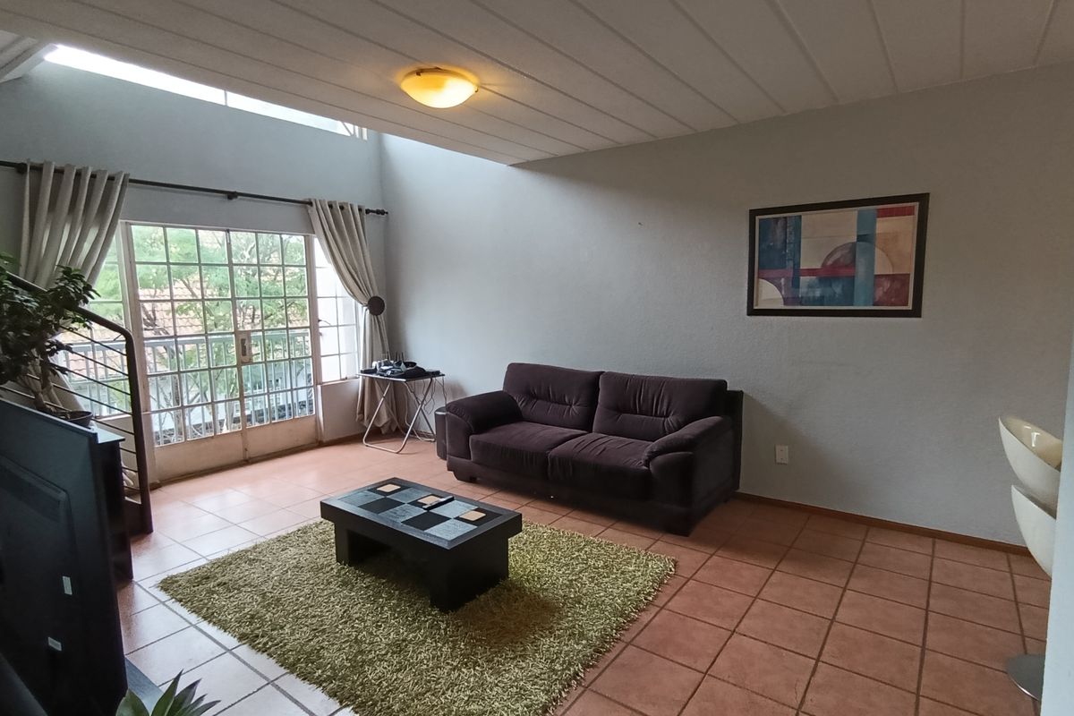Spacious living area featuring tiled flooring, high ceilings, and large glass sliding doors providing access to an outdoor balcony.