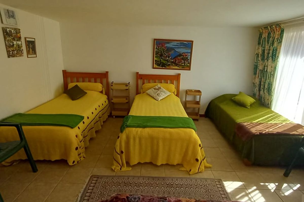 A spacious bedroom featuring tiled flooring and large sliding glass doors that provide ample natural light and access to the outdoors.