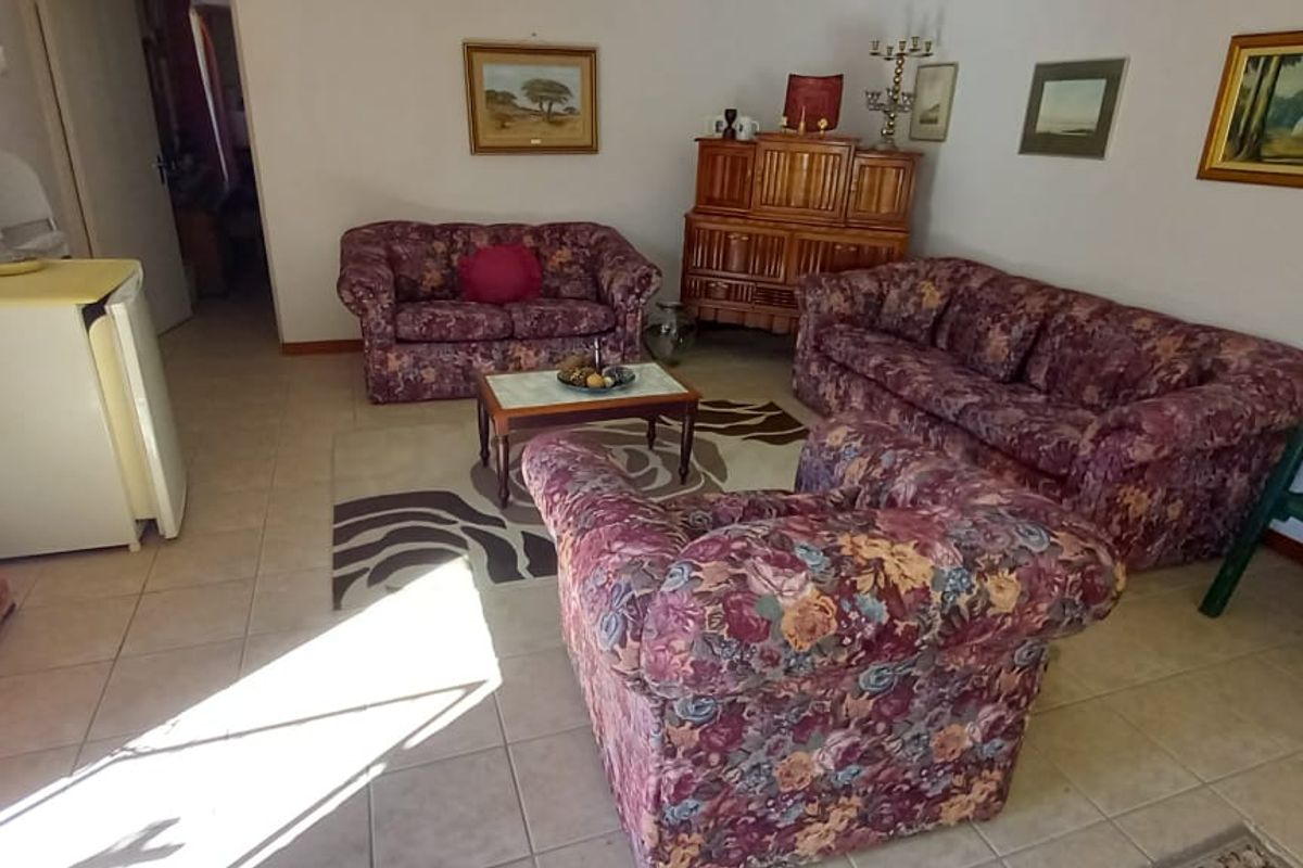 A spacious living room featuring neutral floor tiling and a functional layout, providing a comfortable area for relaxation and daily living.