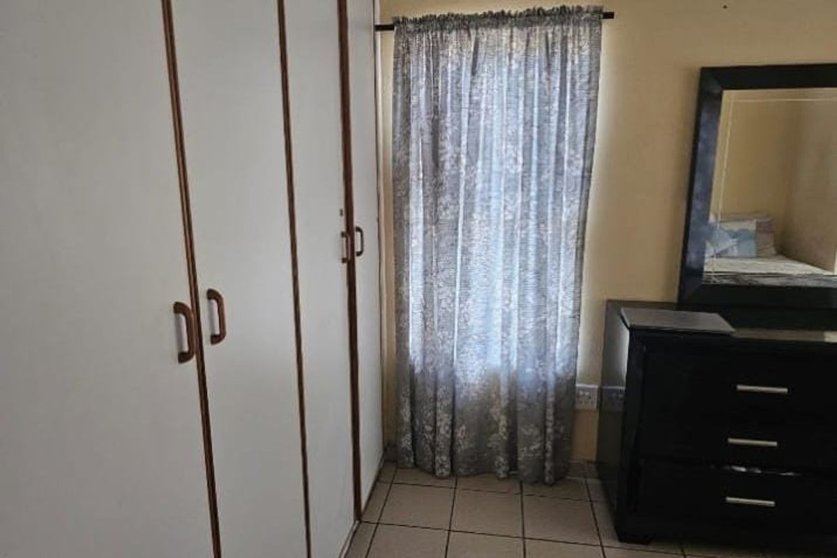A bedroom featuring built-in cupboards and tiled flooring, providing functional storage space.