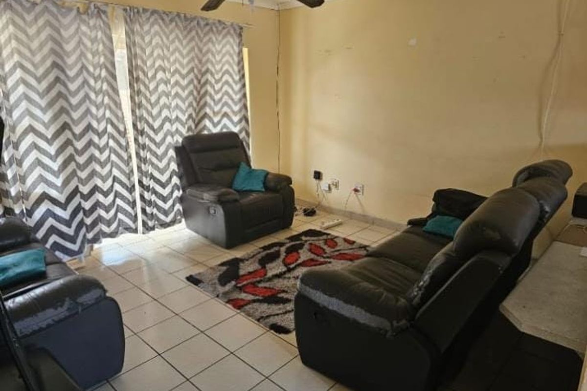 A living room featuring tiled flooring, a ceiling fan, and sliding door access to the exterior.