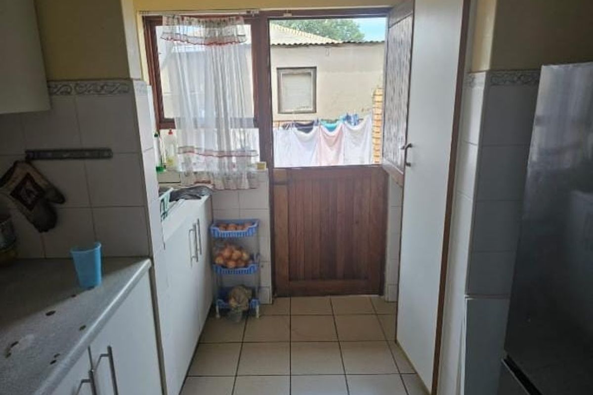 A functional kitchen area featuring tiled flooring, built-in cabinetry, and a stable-style wooden door leading to the exterior.