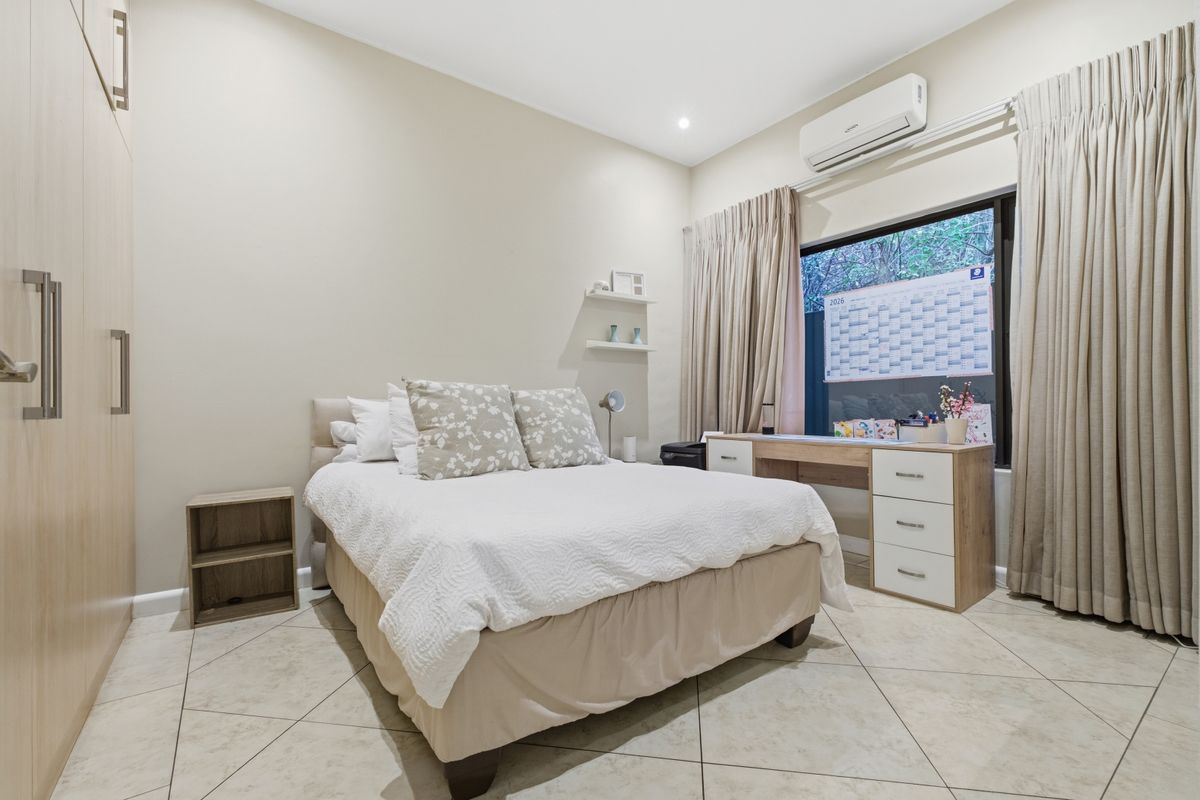 A well-maintained bedroom featuring built-in cabinetry, tiled flooring, and a wall-mounted air conditioning unit.