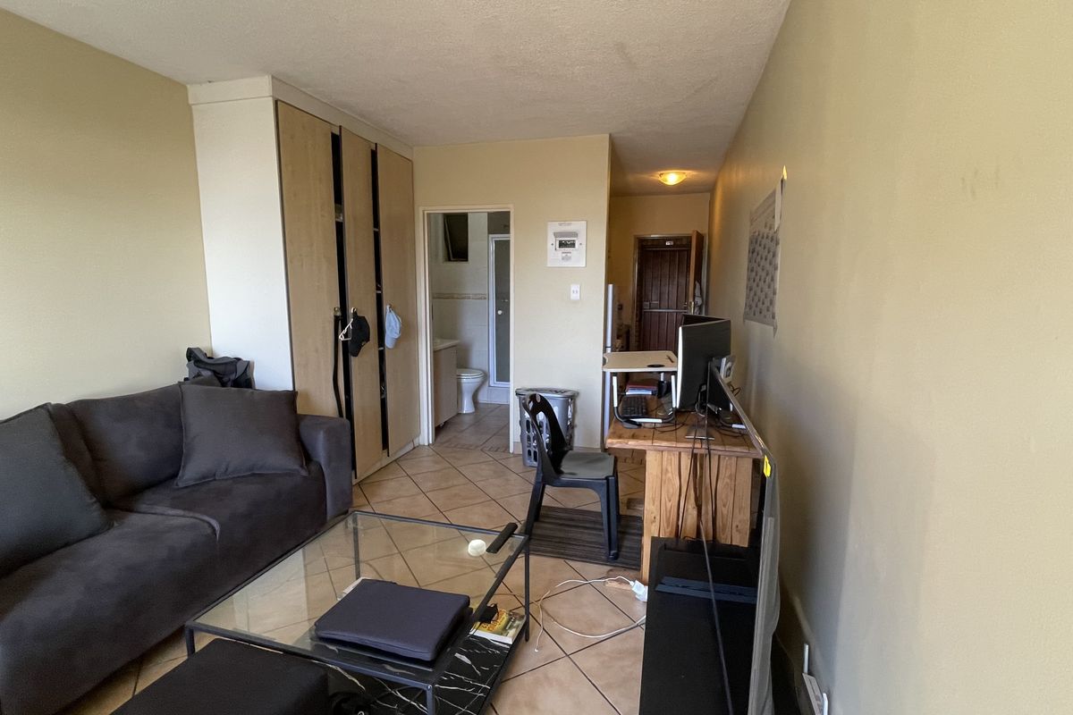 A living area featuring tiled flooring and built-in cabinetry, with an adjacent bathroom visible through the doorway.