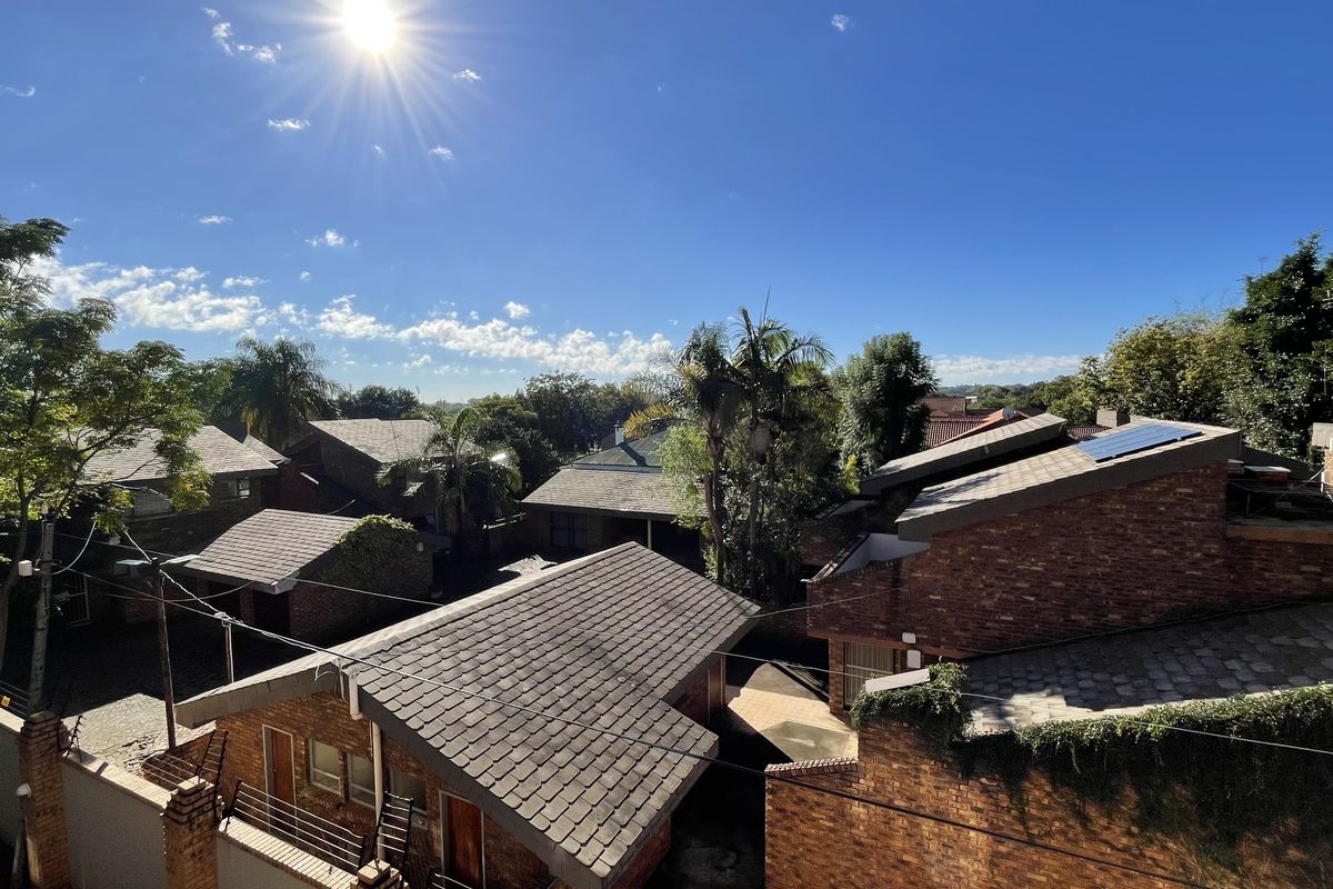 Elevated aerial view overlooking the surrounding residential complex, featuring brick-clad buildings with pitched tiled roofs and established greenery.