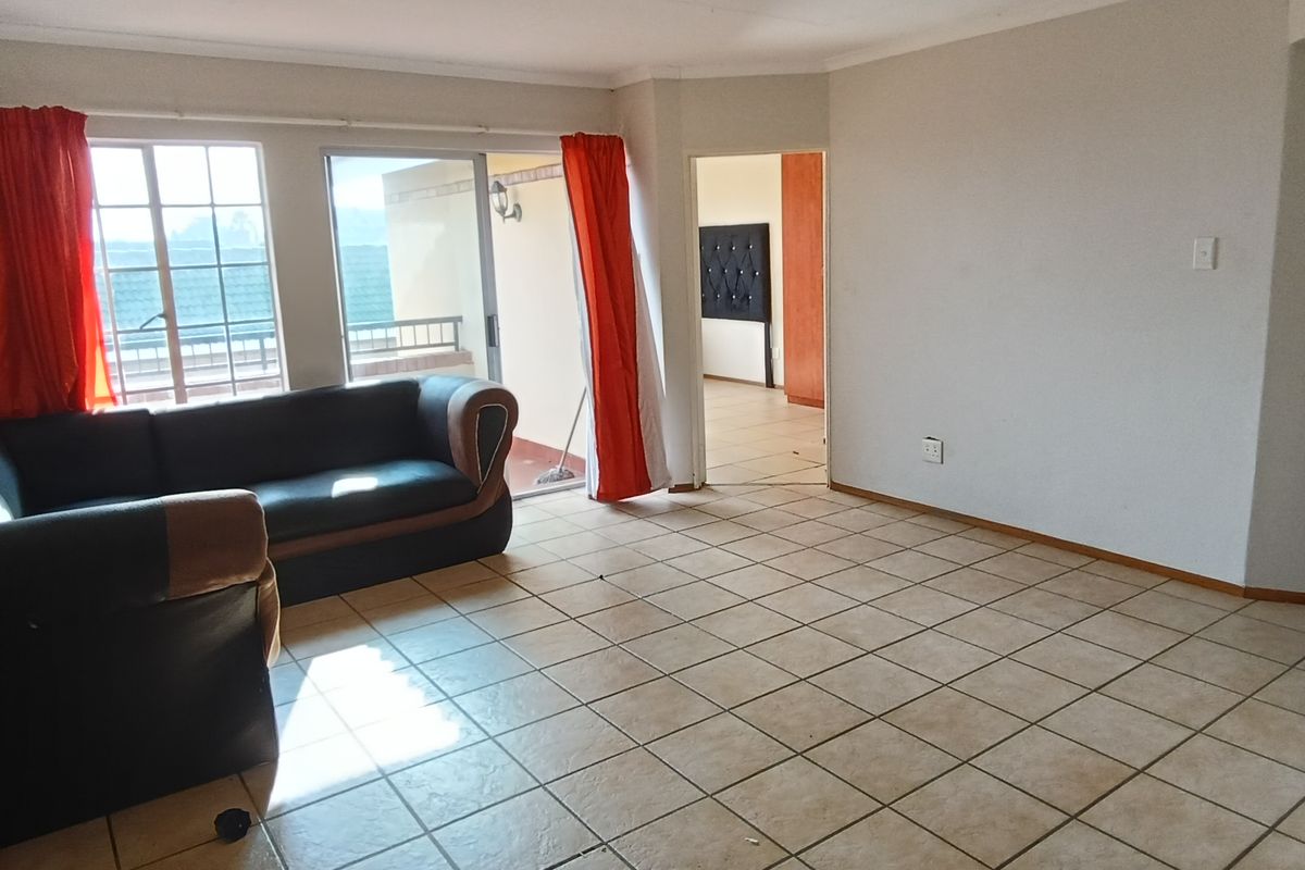 Spacious living area featuring ceramic floor tiles, large sliding glass doors leading to a balcony, and direct access to adjacent rooms.