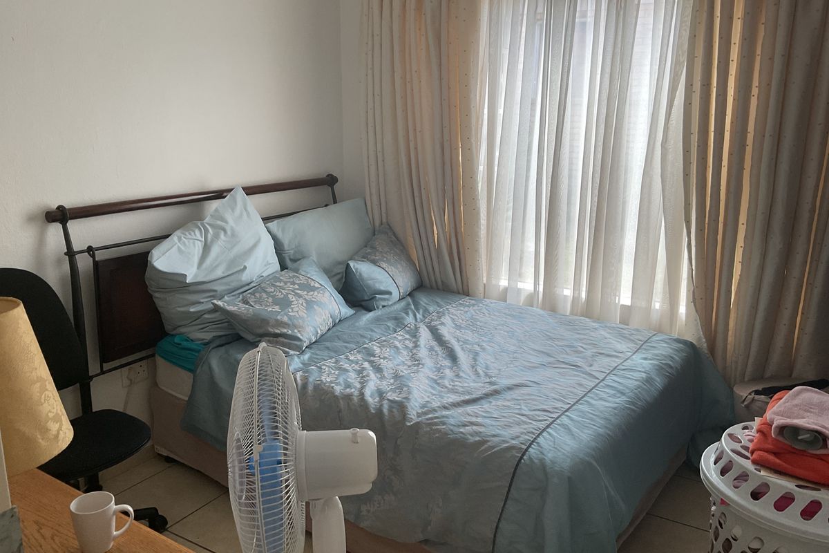 A bedroom featuring tiled flooring and large window with floor-to-ceiling curtains, providing natural light to the space.