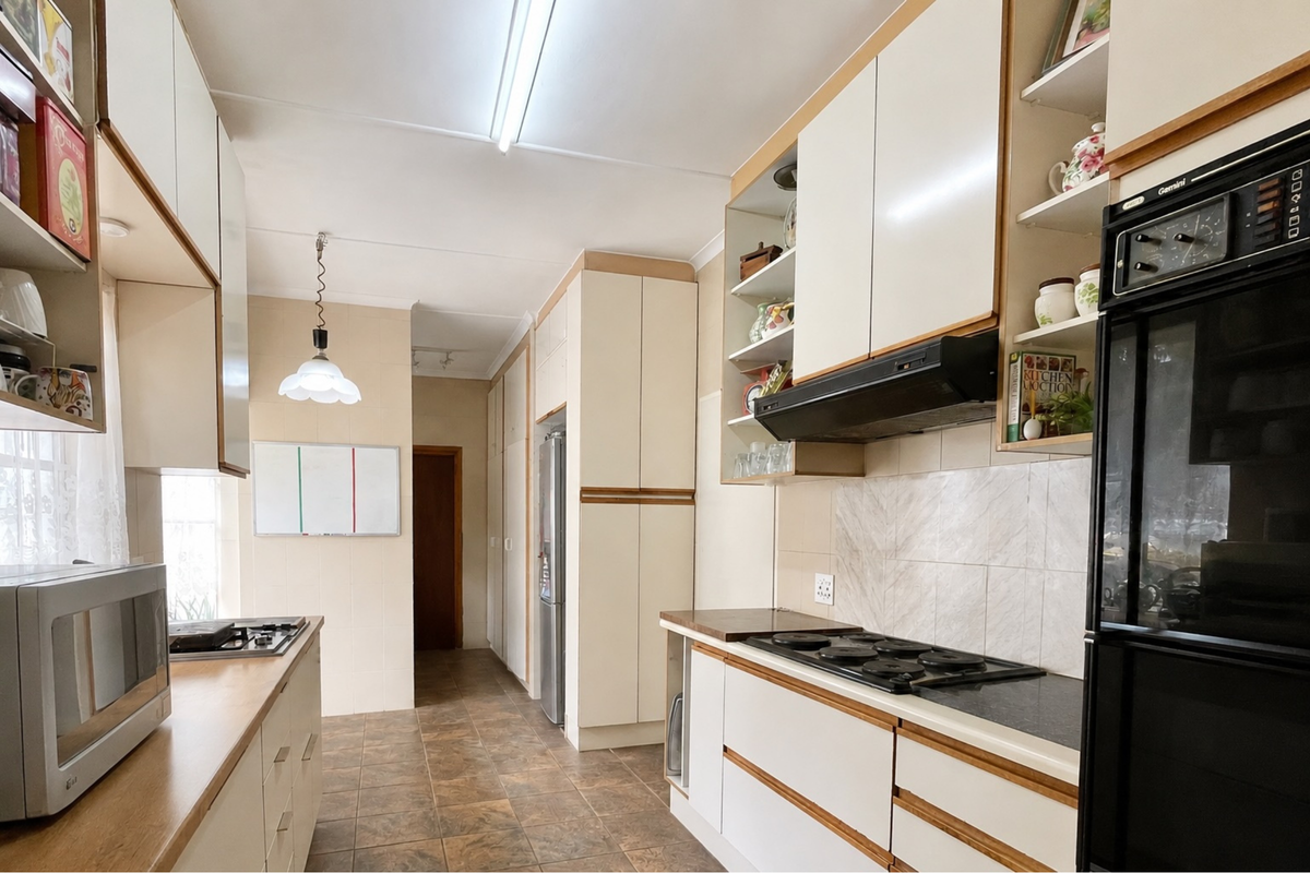 A functional kitchen featuring built-in cabinetry, laminate countertops, a built-in oven, and a hob with an extractor fan, finished with tiled flooring.