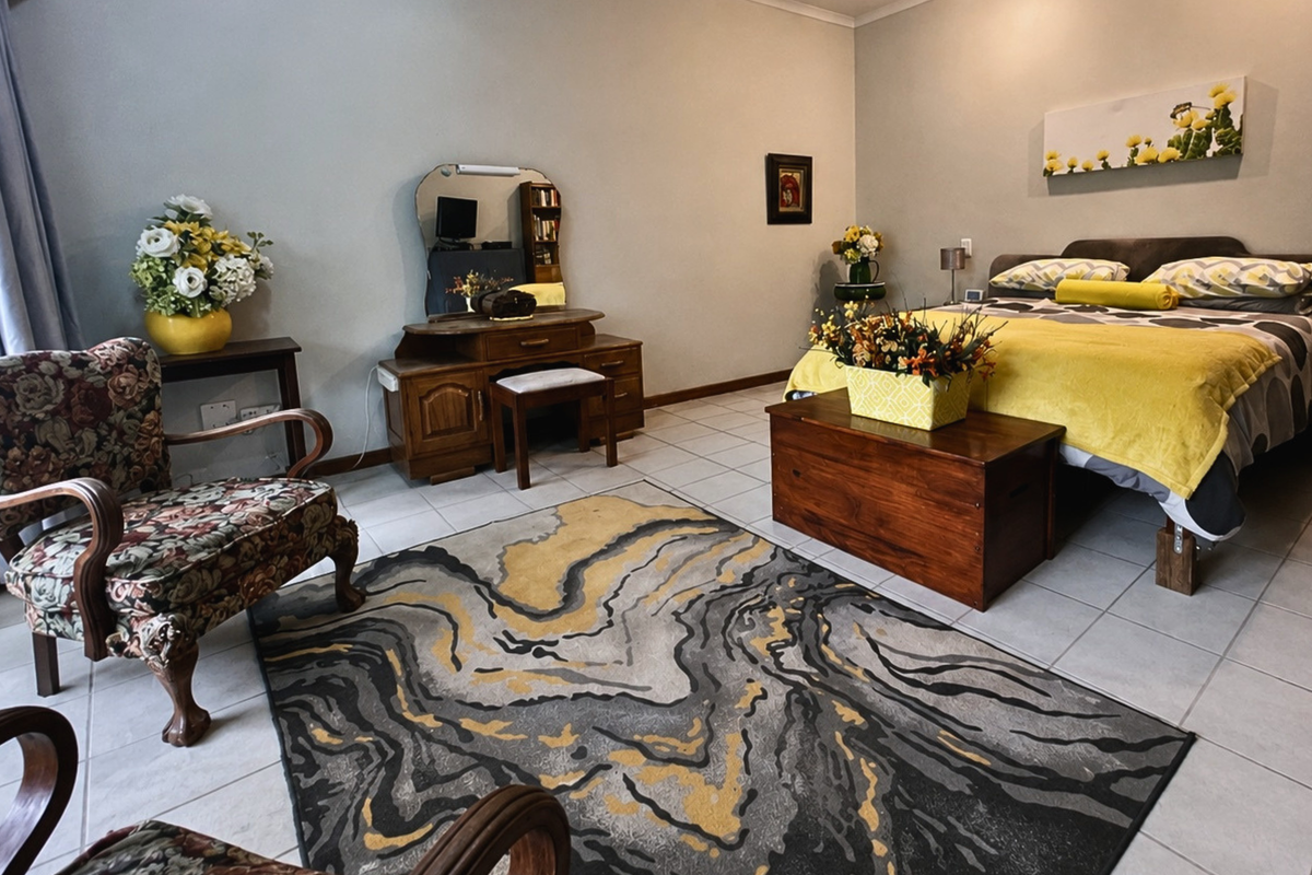 A spacious bedroom featuring neutral wall tones and tiled flooring, offering a comfortable and functional living space.
