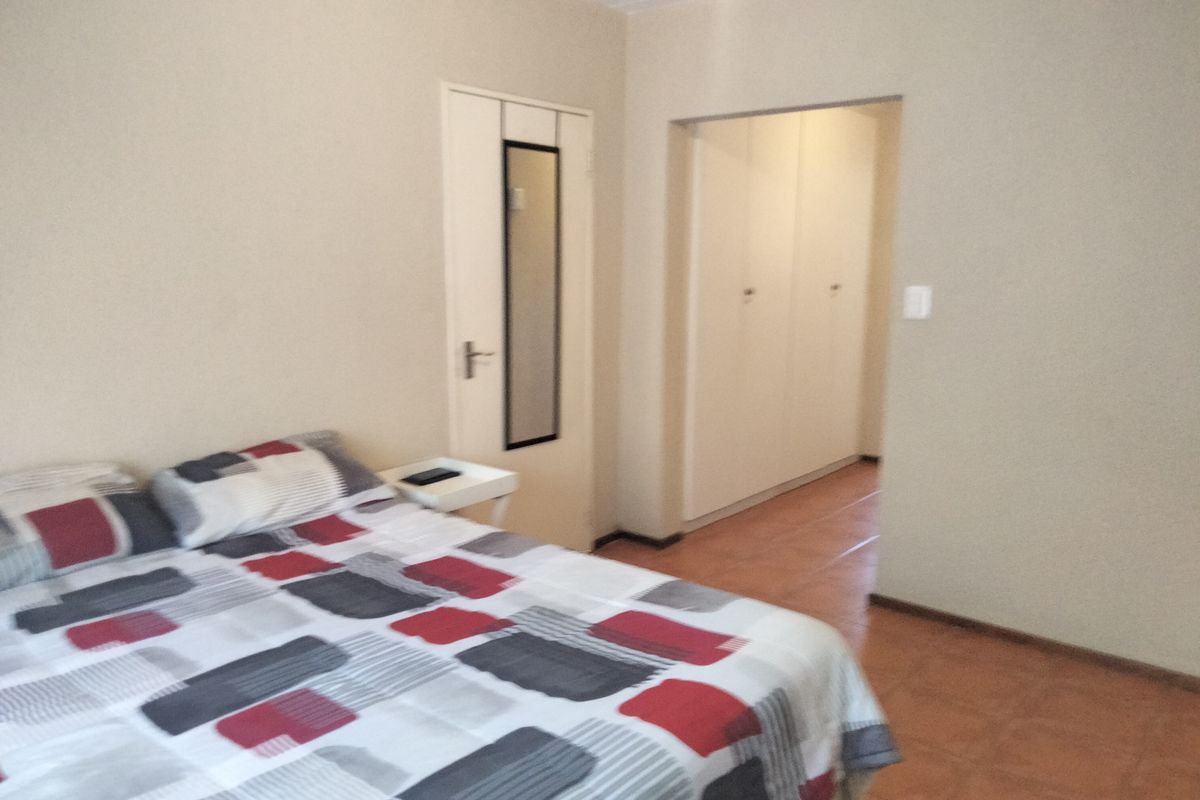 A bedroom featuring tiled flooring and built-in cupboards, with an adjoining walk-through area.