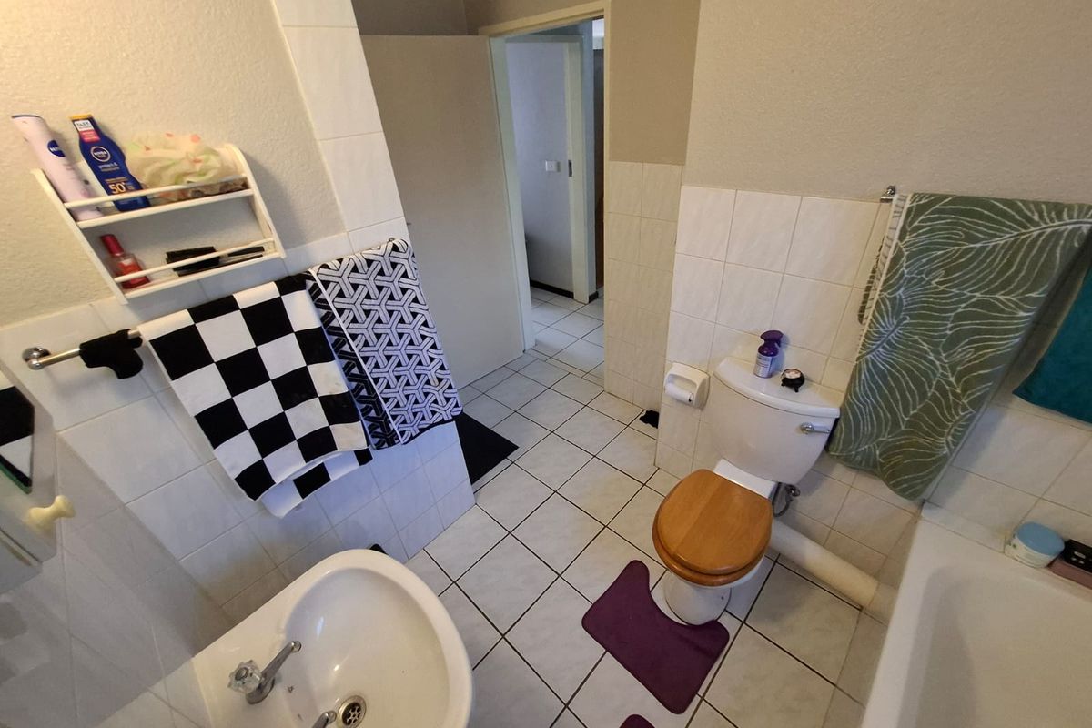 A functional bathroom featuring a standard toilet, pedestal basin, and tiled walls, providing a practical layout for daily use.