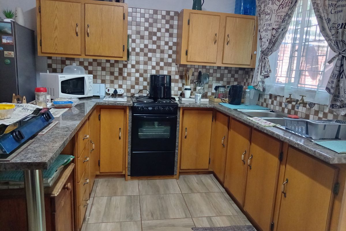 A functional kitchen featuring wooden cabinetry, granite-look countertops, a tiled backsplash, and a freestanding stove with an oven.