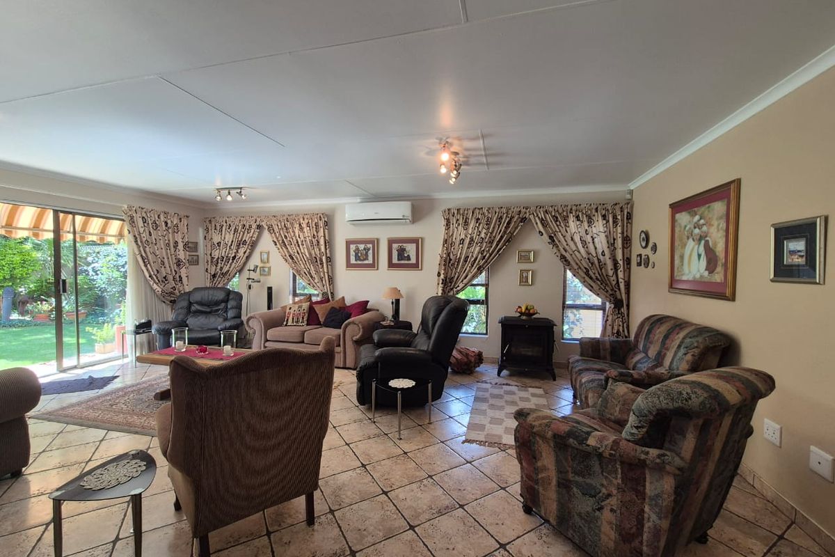 Spacious living room featuring tiled flooring, wall-mounted air conditioning unit, and large sliding glass doors providing direct access to the garden.