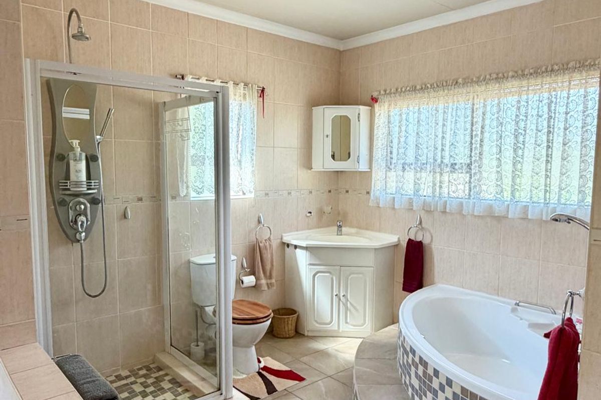 A functional bathroom featuring a corner vanity, a raised platform bathtub with mosaic tiling, and a separate glass-enclosed shower unit.