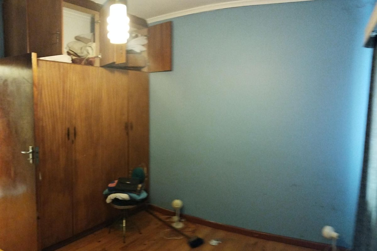 A bedroom featuring original wooden flooring and built-in wooden cupboards with overhead storage compartments.
