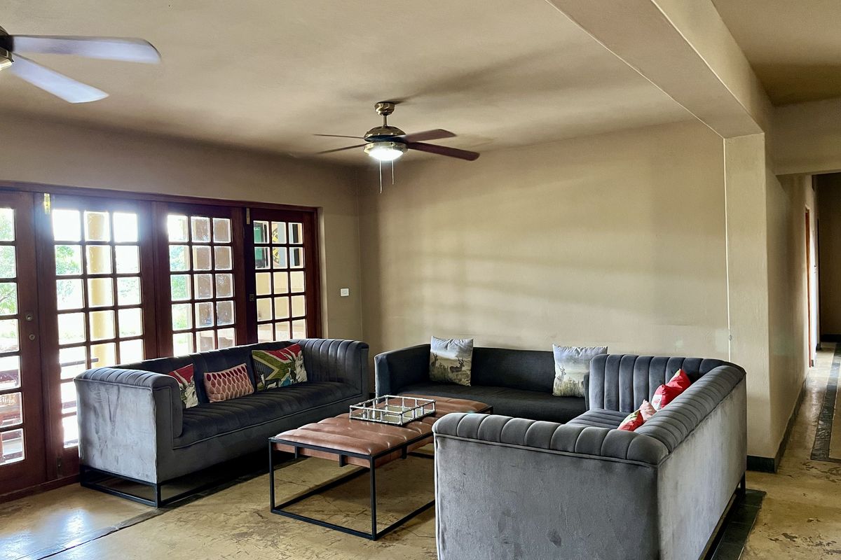 Spacious living area featuring large wooden-framed glass doors providing natural light and a ceiling fan for climate control.
