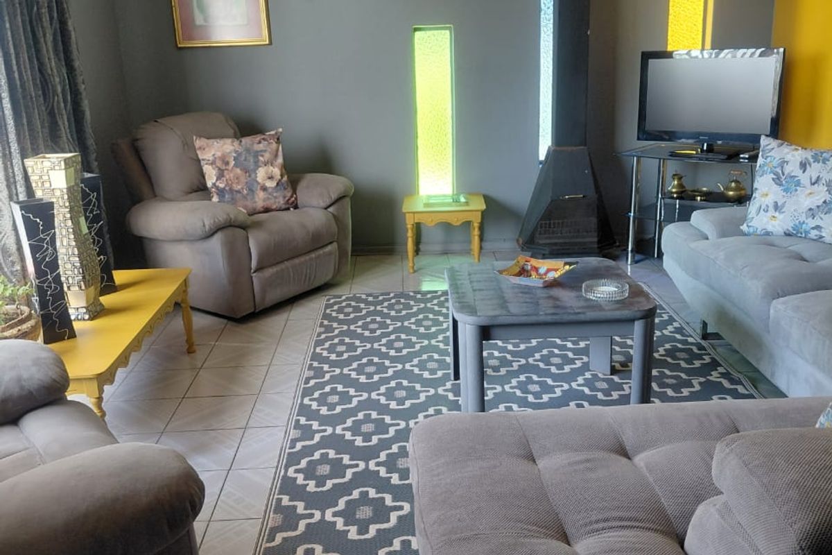 A comfortable living room featuring a built-in fireplace, tiled flooring, and decorative vertical glass inserts.
