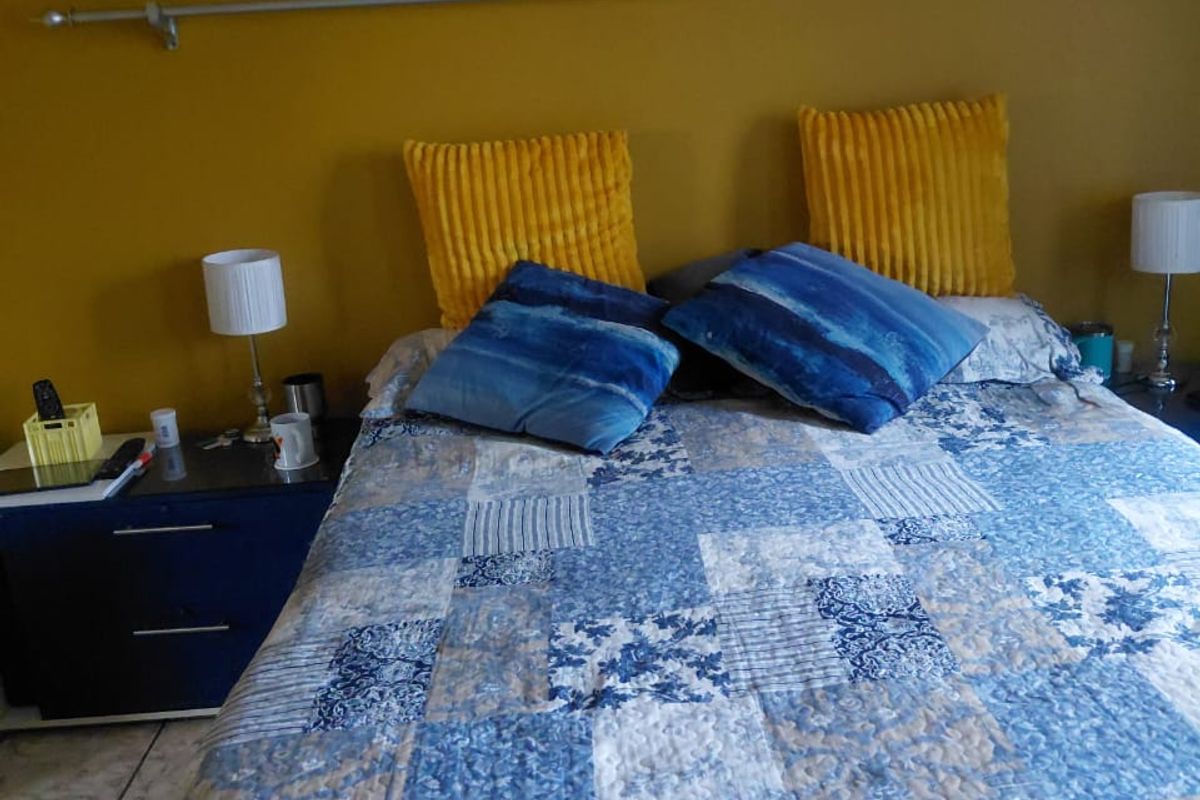 A bedroom featuring tiled flooring and a mustard-colored accent wall with a mounted curtain rod.