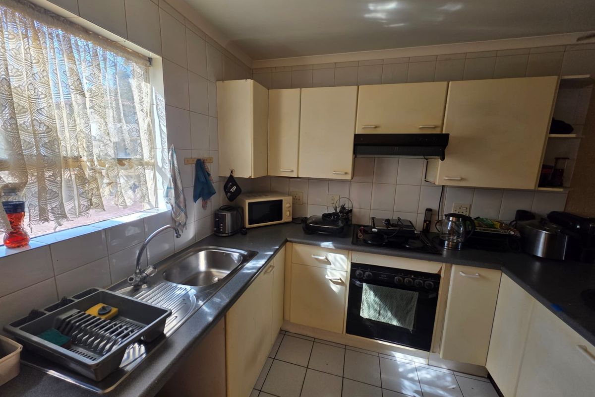 A functional kitchen featuring built-in cabinetry, a stainless steel sink, integrated oven, and hob with an extractor fan.