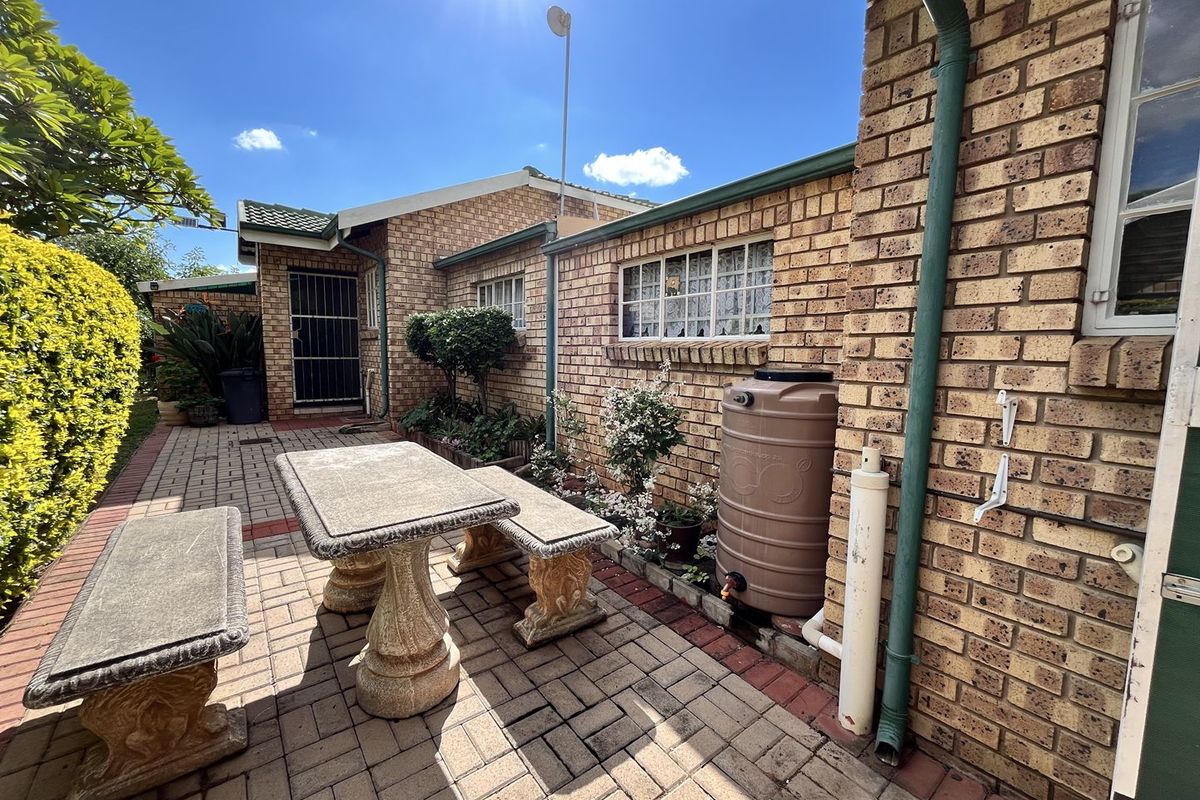 A paved rear courtyard area featuring face brick walls, a rainwater collection tank, and secure access points.