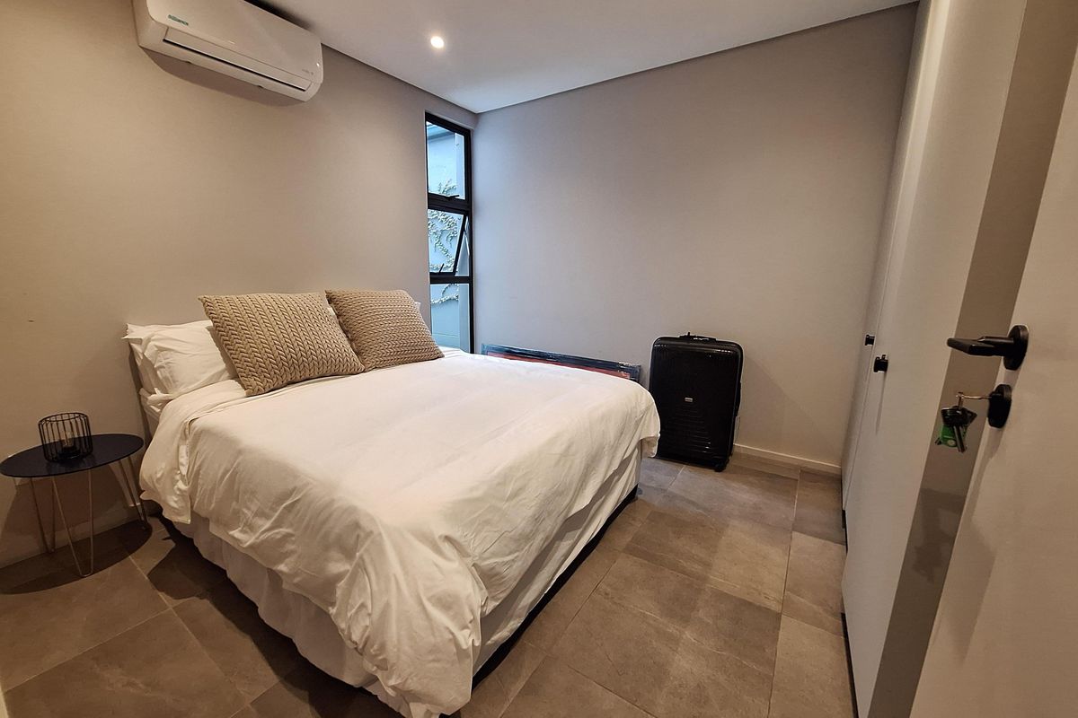 A modern bedroom featuring tiled flooring, built-in cabinetry, and a wall-mounted air conditioning unit.