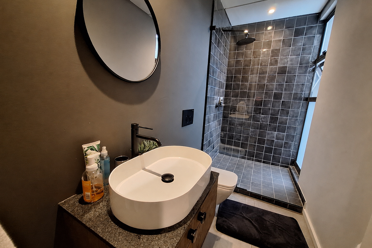 Modern bathroom featuring a vessel sink vanity, dark tiled walk-in shower with glass enclosure, and contemporary matte black fixtures.