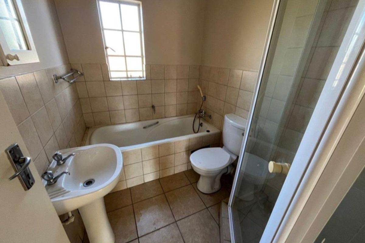 A functional bathroom featuring a pedestal basin, a tiled bathtub, a separate shower enclosure, and a toilet.