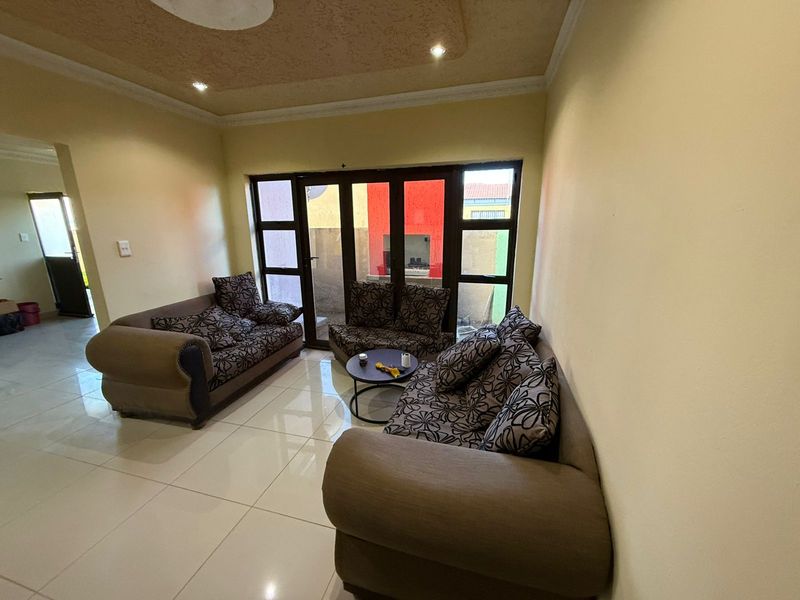 A living room featuring polished floor tiles, recessed ceiling lighting, and large glass sliding doors providing access to an outdoor area.