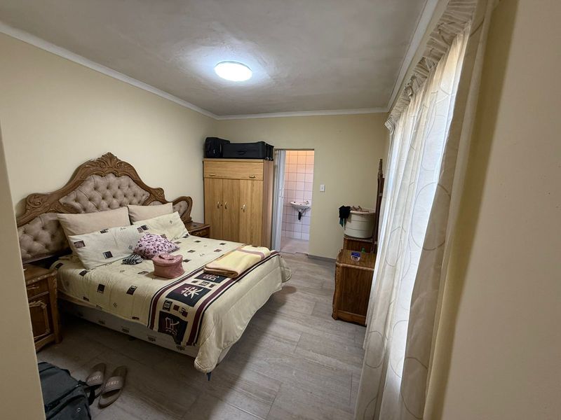 A bedroom featuring tiled flooring and an en-suite bathroom access, providing a functional living space with neutral wall tones.