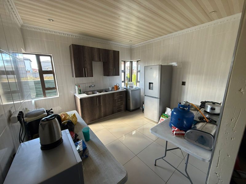 A functional kitchen featuring dark wood-finish cabinetry, tiled walls and flooring, and large windows providing natural light.
