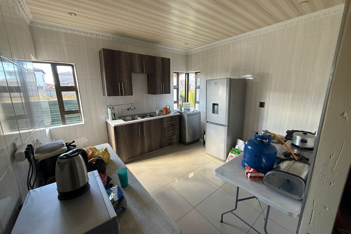 A functional kitchen featuring dark wood-finish cabinetry, tiled walls and flooring, and large windows providing natural light.