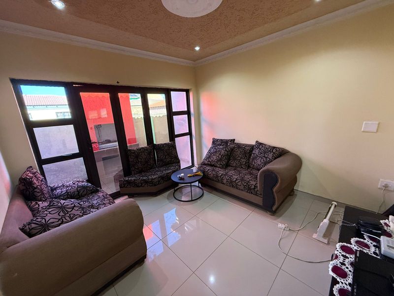 A living room featuring large glass sliding doors providing natural light, tiled flooring, and a decorative textured ceiling finish.